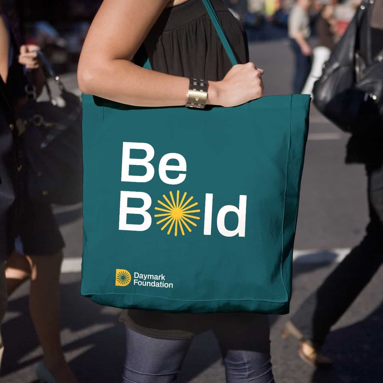 woman carrying a green totebag with Daymark tagline on it