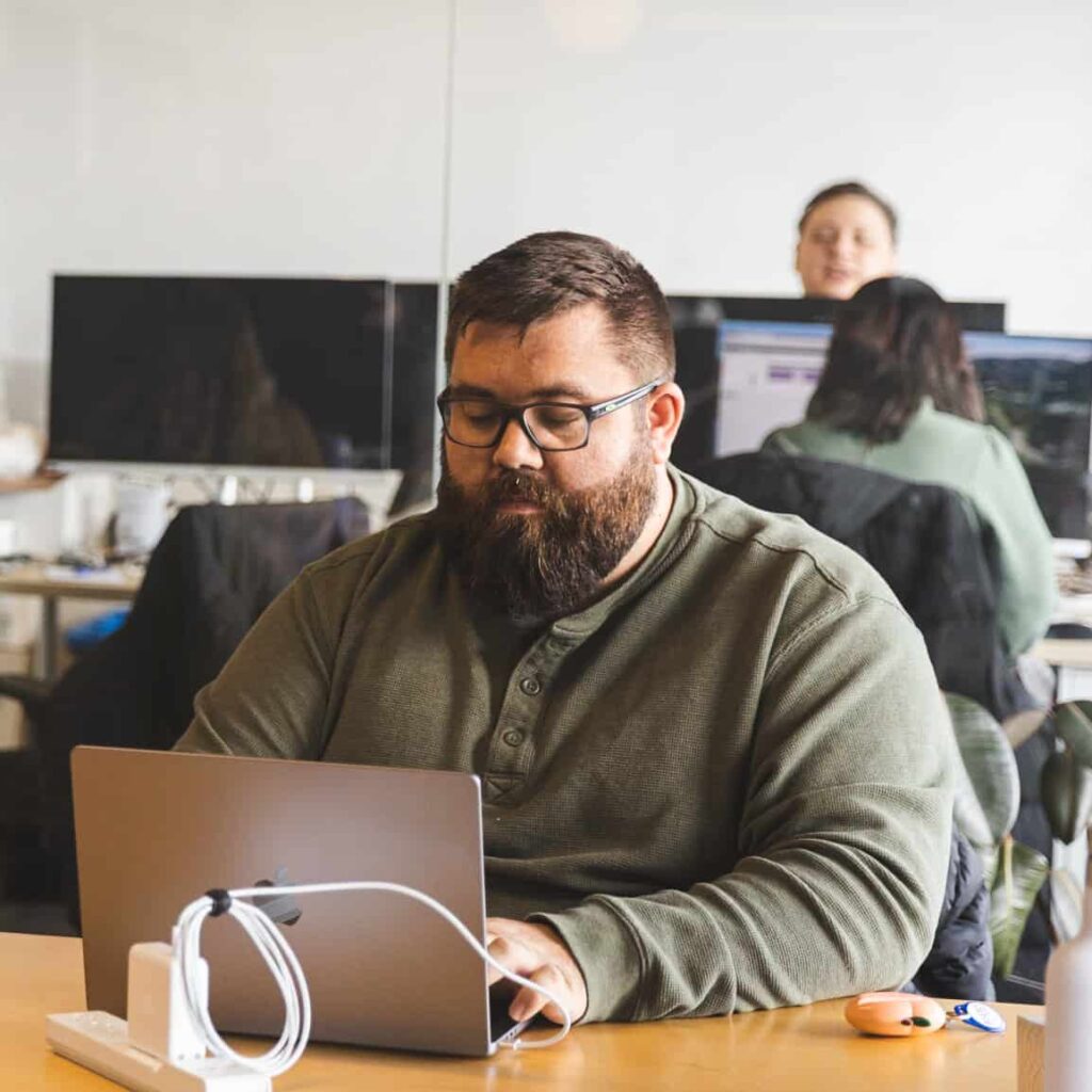 A man working alone on a laptop in an office