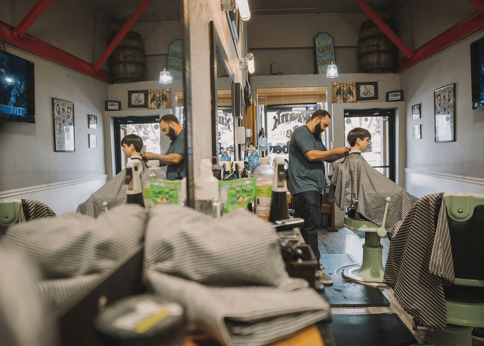 A barber in a barbershop cuts a young boys hair