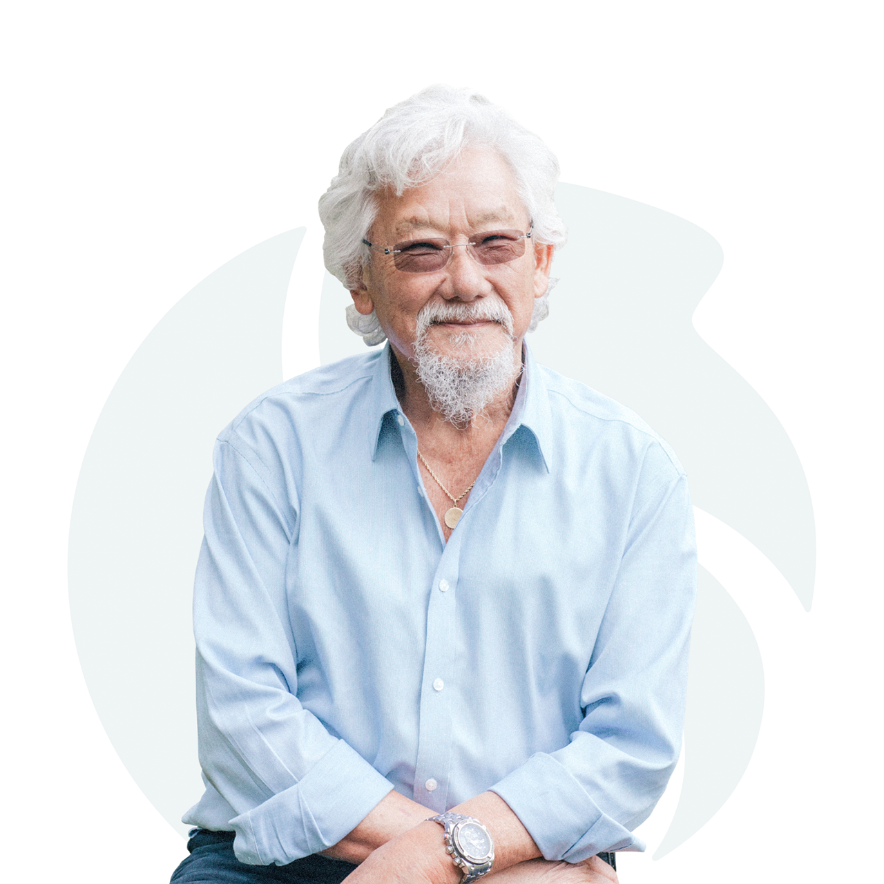 A man wearing a light blue shirt smiles and looks at the camera