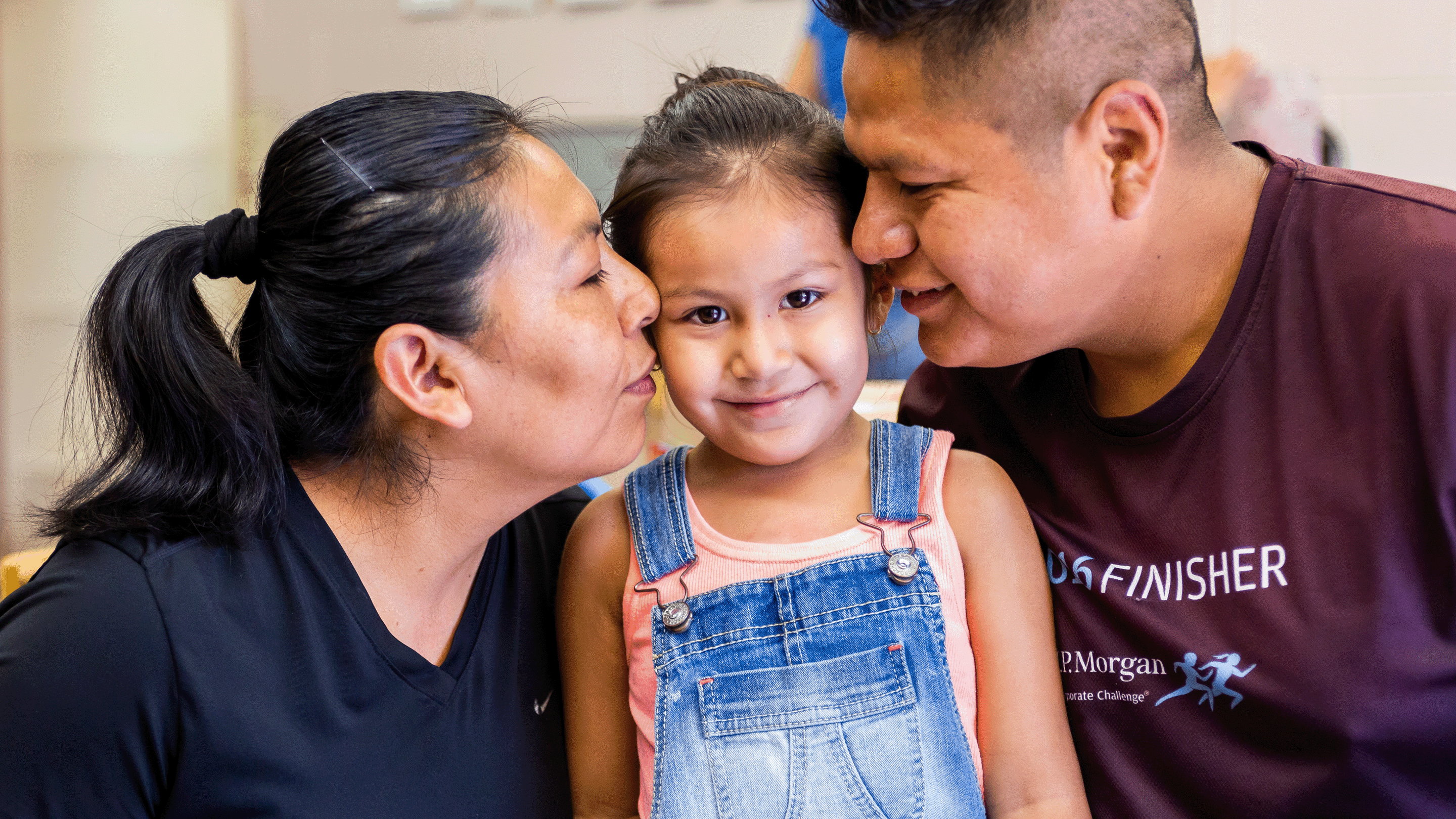 mother and father kiss daughter on the each