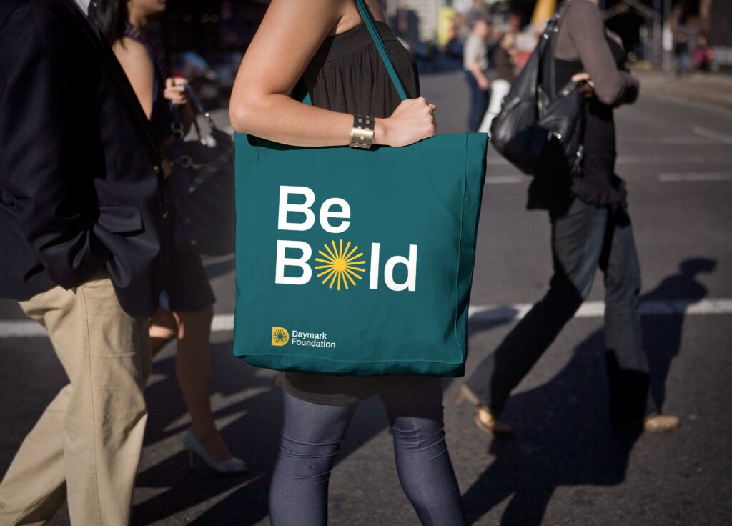 A woman holding a branded tote bag in the street
