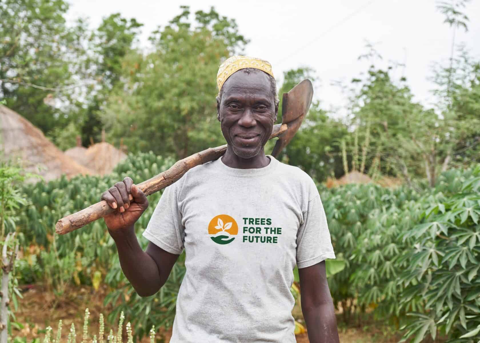 man wearing a trees for the future tshirt and holding a tool to plant trees